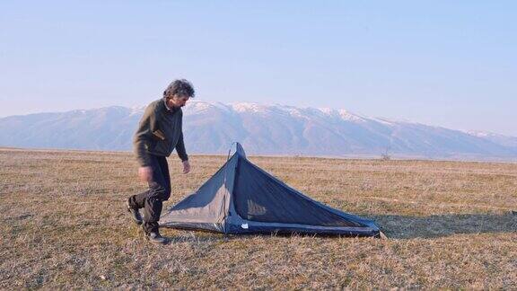 在日落时分在大自然中露营时搭帐篷