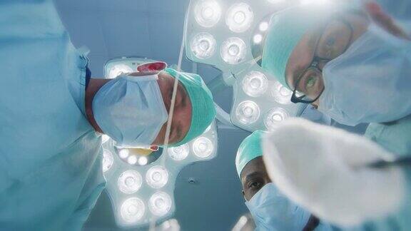 低角度拍摄POV患者视角:三位专业外科医生手持手术器械开始手术