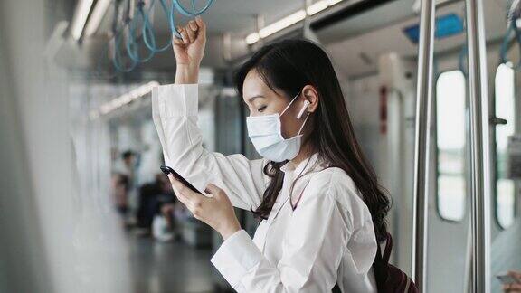 年轻的亚洲妇女戴着口罩在地铁使用电话