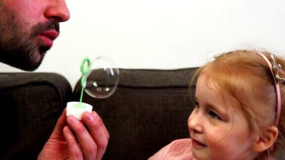 在慢镜头中一位父亲为他的小女儿吹肥皂泡