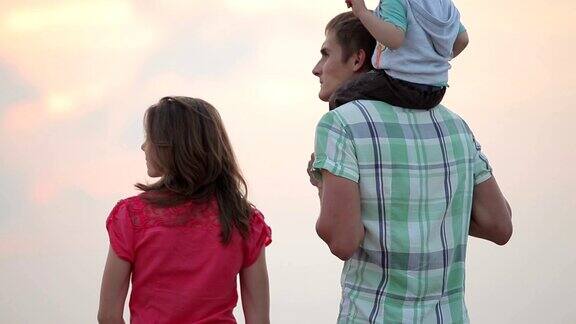 一家人带着孩子在海边看日落互相拥抱