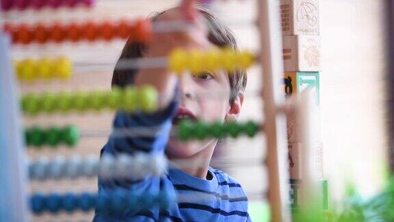 小男孩在学前班使用彩色算盘学习数数(照片摄于真实的美国教室)