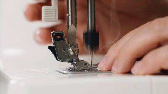 一名女裁缝在缝纫机上缝制白色织物