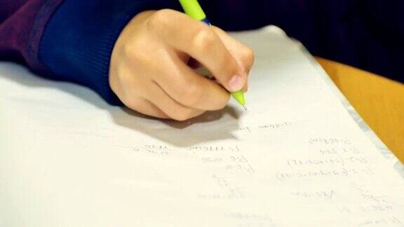 一个小男孩坐在课桌前做着繁重的家庭作业