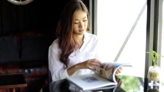 亚洲女性微笑着在咖啡馆里看书放松