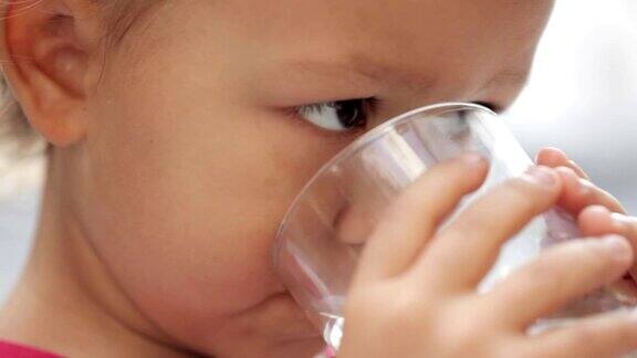 一个可爱的小女孩从杯子里喝纯净水的特写