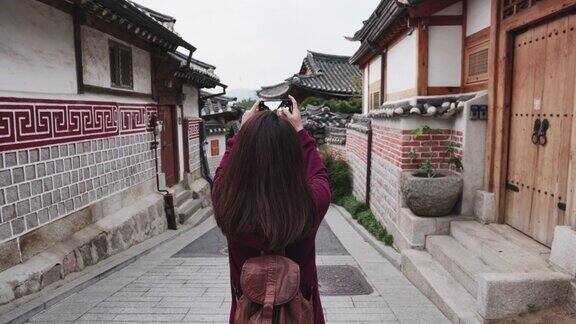 年轻的女游客用智能手机拍下了照片前往韩国首尔市的北川韩屋村