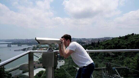 人站在观景台上用双筒望远镜看
