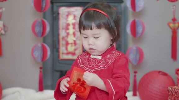 中国一个蹒跚学步的小女孩在家里庆祝春节得到红包