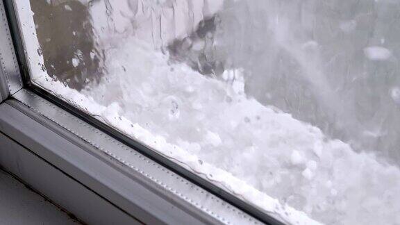 窗外的冰雹一些冰雹落在一扇塑料窗户后面的窗台上