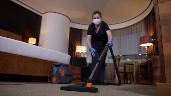勤劳的服务员用吸尘器清扫酒店房间的地毯
