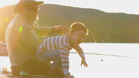爷爷和孙子在夏天的日落钓鱼