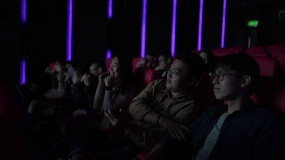亚洲华人混合年龄段的观众在电影院排成一排享受和观看电影