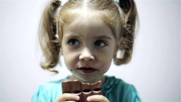 小女孩吃巧克力孤立在灰色背景
