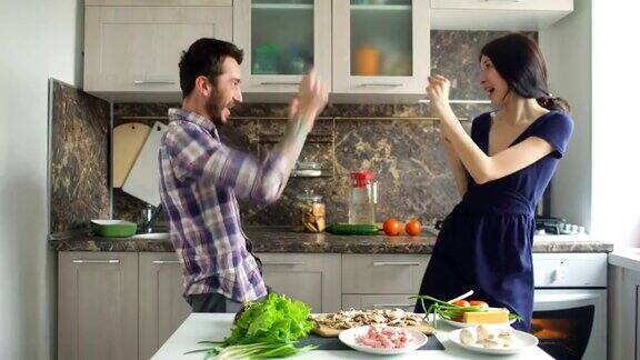 幸福美丽的夫妇跳舞摇滚同时在厨房做饭在家
