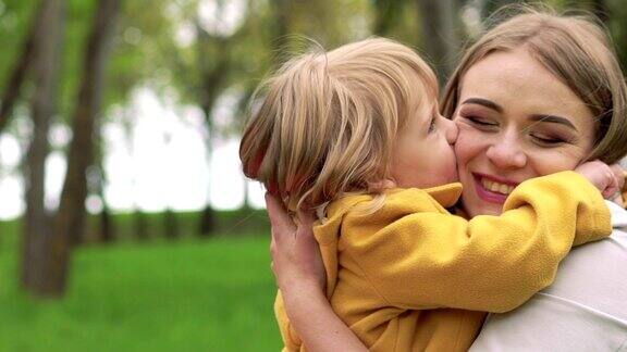 小女孩在公园里拥抱妈妈亲吻她慢慢地