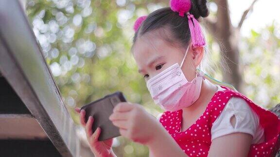 亚洲小女孩戴着防护面罩打算看手机