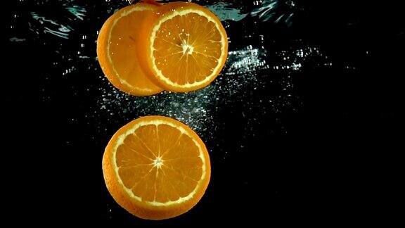 三片橘片在黑色背景下飞溅入水中动作非常缓慢