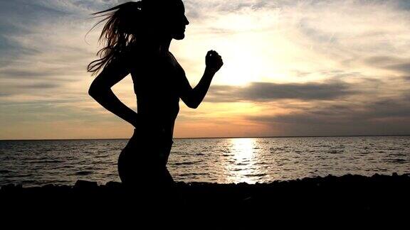 日落时分年轻的健康女子在海边慢跑