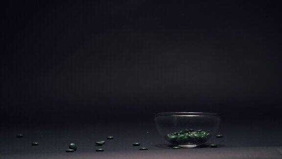 绿色糖果在玻璃碗中缓慢落下复制空间在黑色黑板纹理背景上
