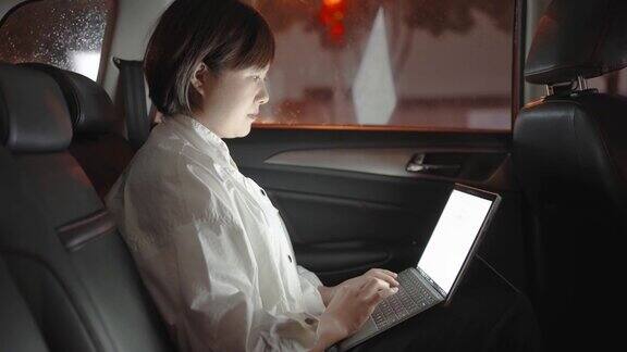 一个女人在车后座上用笔记本电脑