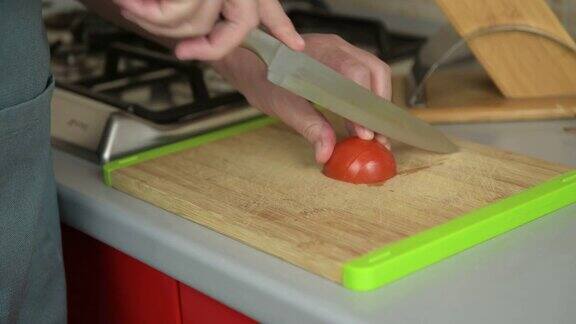 真正的男性用手在砧板上切西红柿