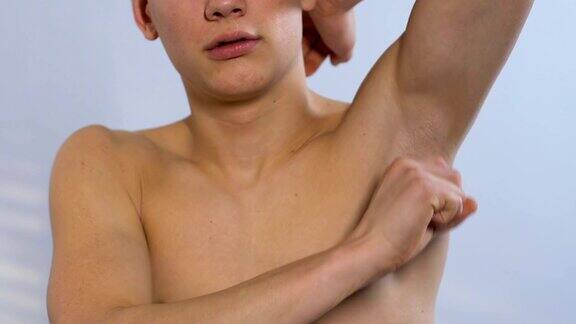 赤裸上身的青少年在腋下涂抹除臭剂准备在健身房锻炼