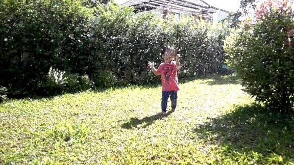 小男孩在花园里玩洒水器慢镜头全高清