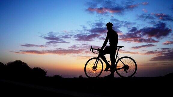 日落时岩石上骑自行车的人的剪影