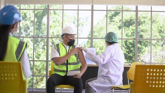 工人在接种冠状病毒疫苗时看着和护士注射疫苗以保护病毒获得免疫力工业工厂诊所保健的基本工作人员接种疫苗