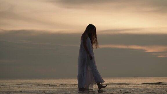 一个穿白裙子的女人在海边散步