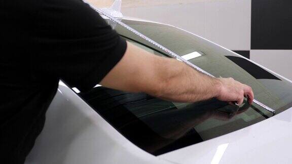一名男性汽车修理工在上着色膜之前测量了一下后挡风玻璃