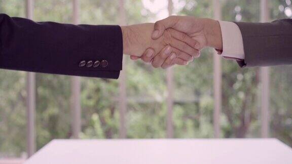 慢动作在招聘会议后握手以达成协议两个自信的亚洲商人在办公室开会时握手成功交易问候和合作伙伴