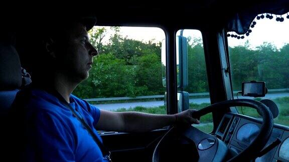 日落时分卡车司机在乡间行驶的侧面图戴着帽子的人控制着他的卡车注意观察着道路货车车厢内的景象货物运输慢镜头