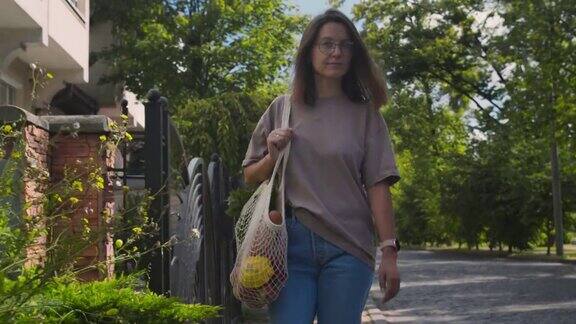 一名妇女用可重复使用的细绳袋携带食品杂货