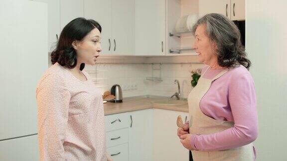 年迈的母亲在厨房里围着围裙和女儿争吵代沟冲突