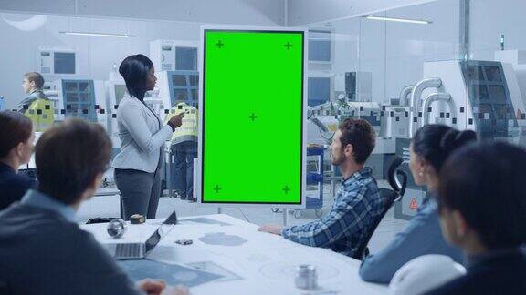 在会议上总工业工程师向一组专家、经理报告使用绿色屏幕色度键显示的数字白板专业人士在现代工厂办公室中寻找解决方案