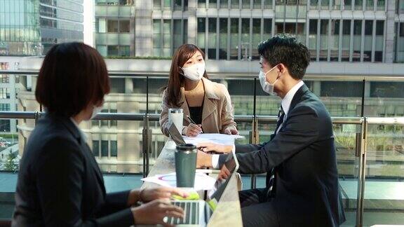 在亚洲商务人士开会时要戴着防护面具保持社交距离