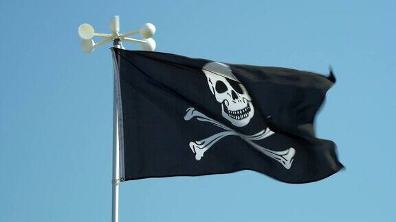 蓝色的天空映衬着黑色海盗的海盗旗移动带有海盗标志的海盗船的旗帜