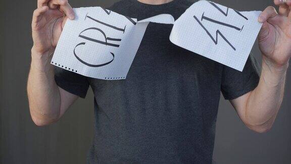 男人的手撕纸与危机标志在方格纸上灰色背景的慢动作完成了金融危机阻止经济问题