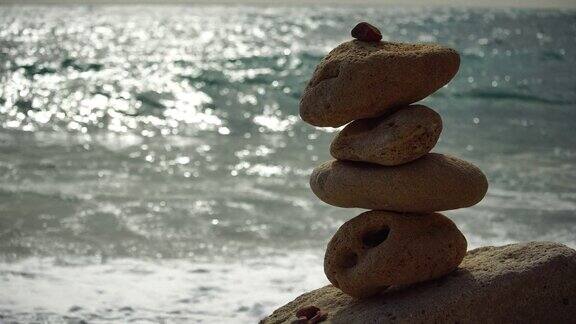 在一个阳光明媚的日子平衡的卵石金字塔在海滩上背景是大海的泡沫有选择性的重点海滩上的禅石冥想水疗和谐平静平衡