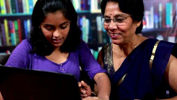 快乐的印度老年妇女和她的孙女使用笔记本电脑