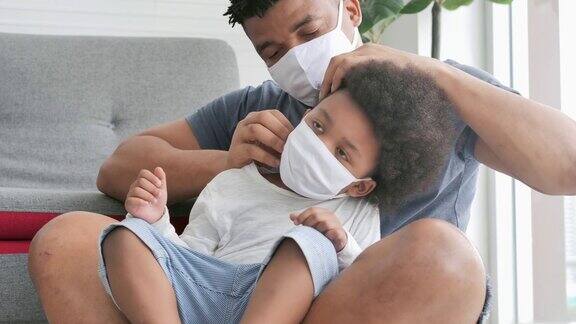 一个非洲家庭的父亲为他的小儿子戴上医用口罩呆在家里防止冠状病毒或新冠肺炎的流行父亲和小男孩在一起口罩及面罩(非白种人)