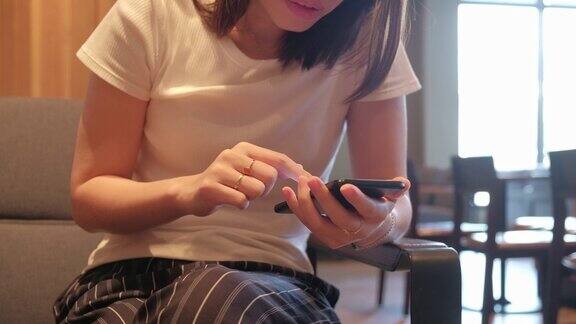 亚洲女性在咖啡店用智能手机进行社交媒体