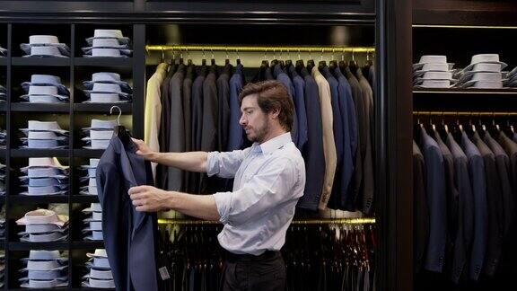 年轻的男性顾客在一家男装店看西装