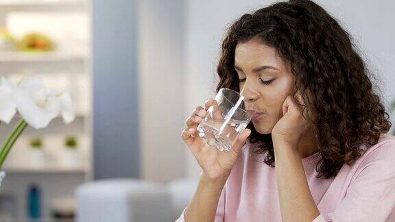 漂亮的混血女性喝着平静的水享受着健康的生活方式