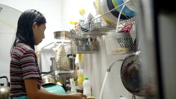 亚洲女孩在家里的厨房里洗盘子家务观念