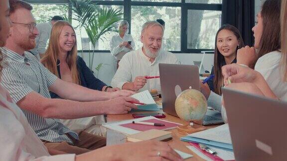 快乐的中年老板商人团队领导激励开朗的多元化经理在办公室桌子会议慢镜头