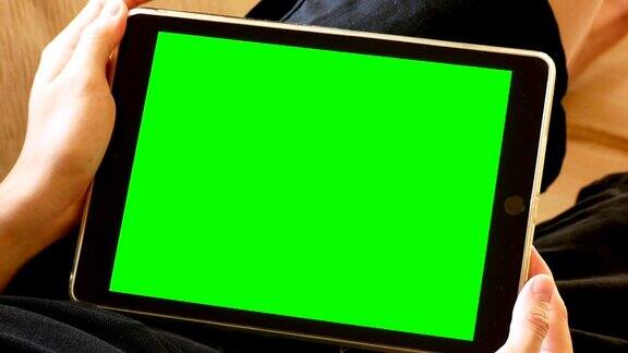 男人躺在沙发上拿着绿色屏幕的数字平板电脑
