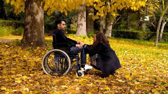 轮椅上的残疾人和女朋友在秋天公园